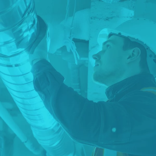 Technicien casqué inspectant un conduit de ventilation institutionnel