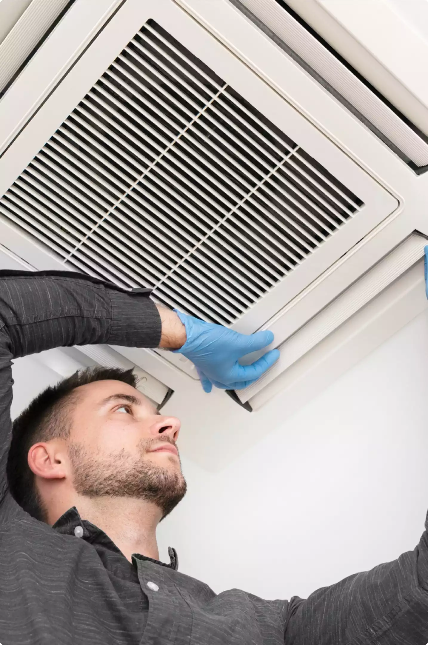 Technicien retirant une grille de ventilation au plafond pour un nettoyage NADCA