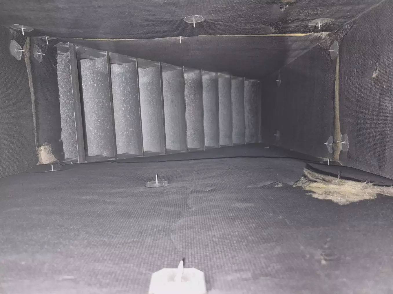 Intérieur d'un conduit de ventilation industriel propre après nettoyage, déflecteurs métalliques dégagés